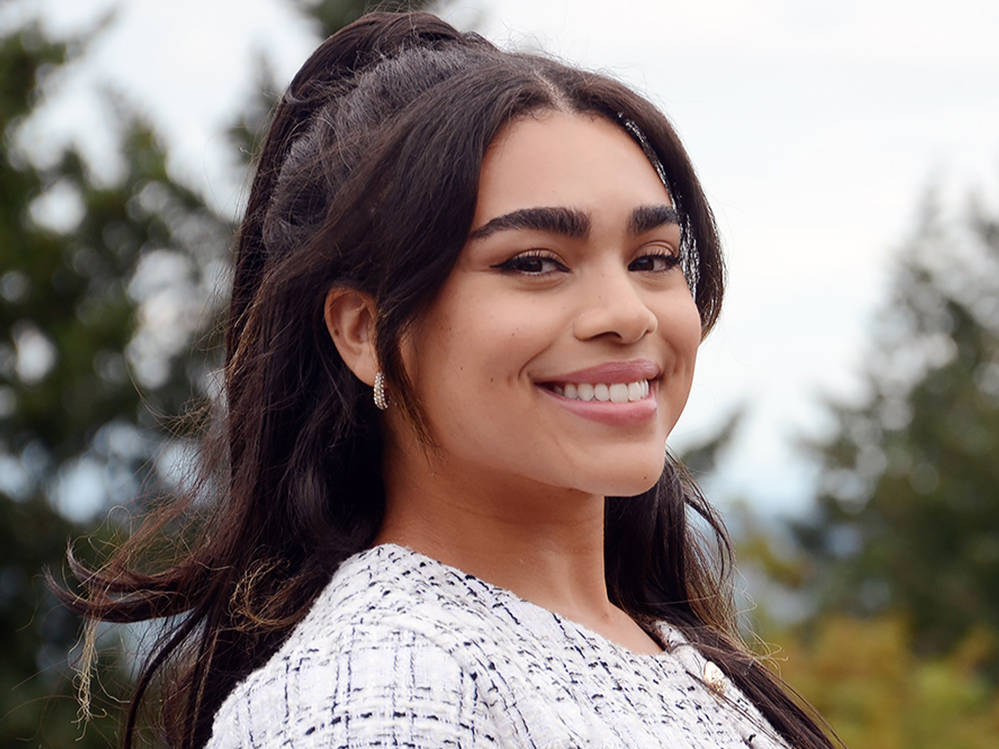 Nursing student Kiara Morelli smiles at the camera with tall trees in the background