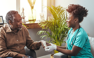 Closeup shot of a young woman holding a senior man's hands in comfort. Female carer holding hands of senior man