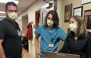 Three team members gathered aroun laptop, smiling