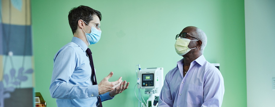 博彩网站 cancer expert Marshall Strother gestures with his hands while talking to a seated patient.
