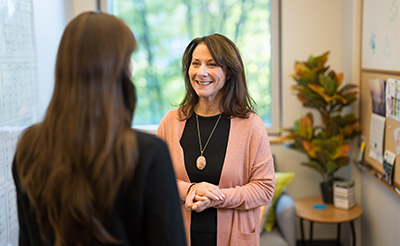 Professor Leslie Hammer talking with a student in an office.