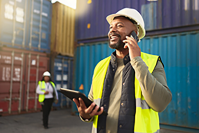 Transportation engineer on smartphone in delivery, freight and international distribution business in container yard