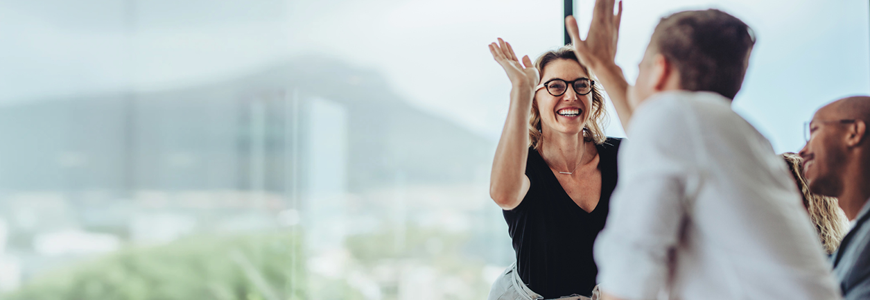 Business professionals high five during a meeting in boardroom