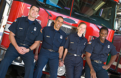 Firefighters standing next to a fire engine.
