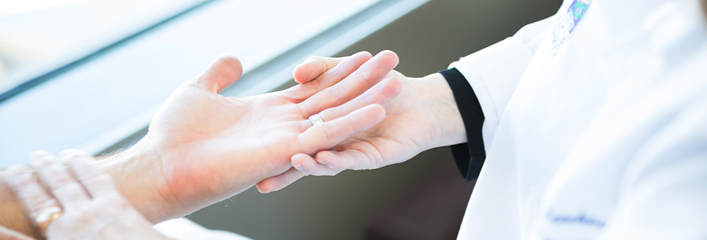 A doctor inspects the hand of a patient