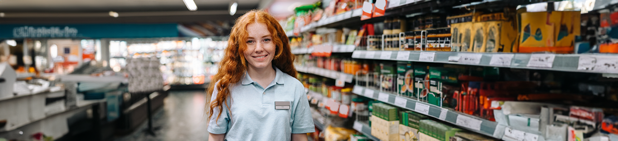 Happy young saleswoman in modern supermarket.