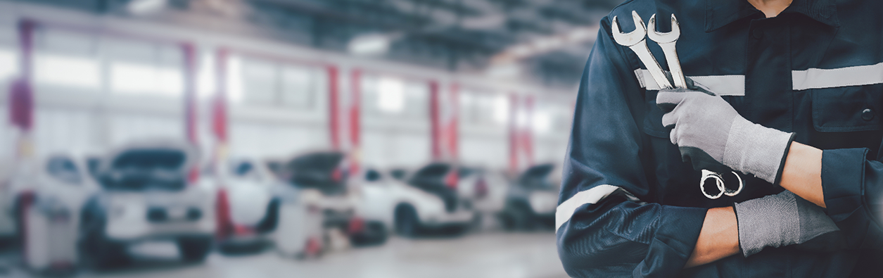 Hands of car mechanic with wrench in garage.