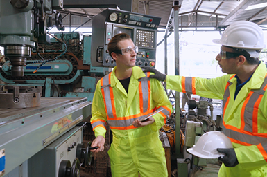 Factory worker warn coworker about safety and give hardhat to him. Injury prevention and safety first concept