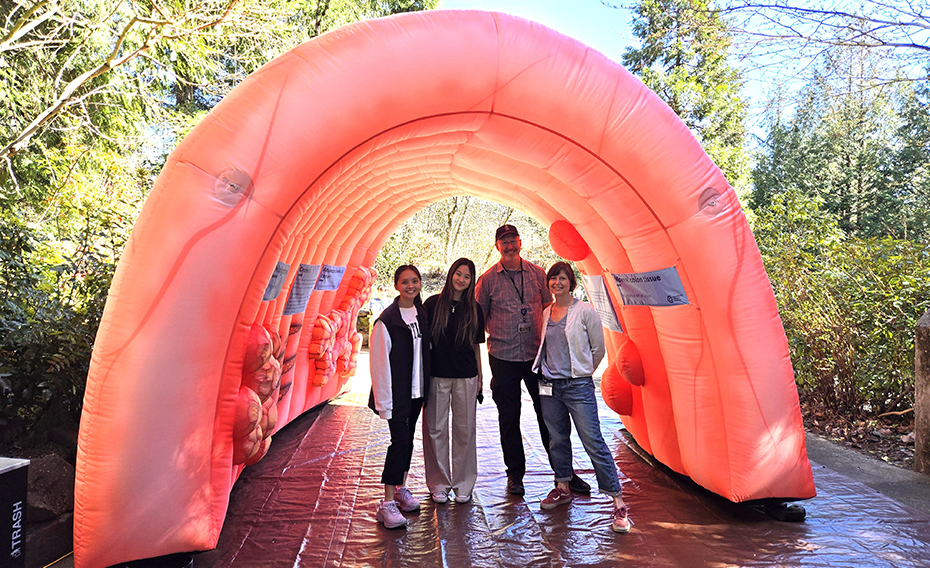 4 people stand under an 8-foot-tall inflatable colon