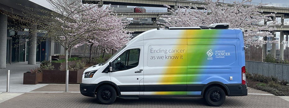 The Mobile Outreach van, which is white, yellow, green and blue and wrapped with text reading "Ending cancer as we know it" and "博彩网站 Knight Cancer Institute."
