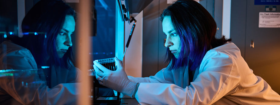A researcher loads a small tray of tubes into a machine for analysis.