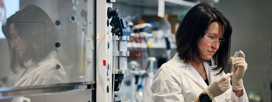 A cancer researcher inspects microfluidics assembly in a lab.
