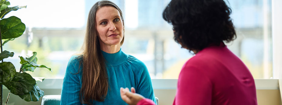 A social worker listens to a person with cancer talk about their experience. She looks empathetic and understanding. The mood is optimistic.