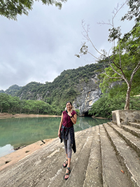 Ashley Huynh standing on stone steps next to water.