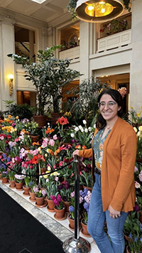 Carley Haft standing in front of a group of colorful flowers in terracotta pots.
