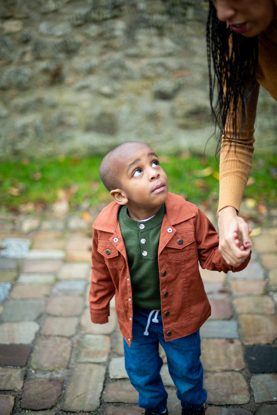 little boy holding parent's hand and looking up