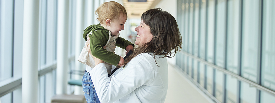 博彩网站 surgeon Lori K. Howell holds a toddler and shares a smile with him.