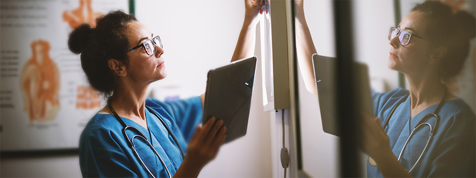 An 博彩网站 nursing student wearing scrubs and a stethoscope reviews a patient’s chart.