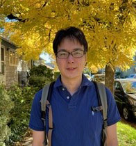 Headshot of JADECOM Fellow Hiroto Inoue with blue polo shirt and fall leaves behind him
