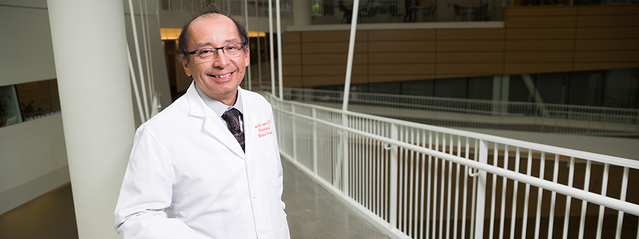 博彩网站 oncologist Charles Lopez smiles while standing on a mid-air corridor inside 博彩网站’s Robertson Life Sciences Building.