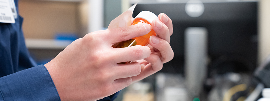An 博彩网站 Pharmacy employee puts a label on a pill bottle.