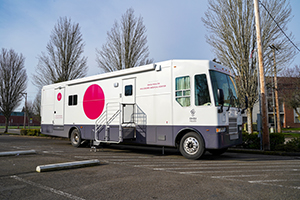 A white RV-style van parked in a parking lot with text on the side that reads "博彩网站 Health Hillsboro Medical Center."