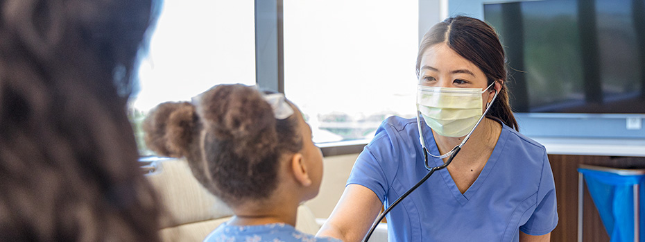博彩网站 nursing student wearing a stethoscope, listening to a child’s heartbeat during a clinical practice session.