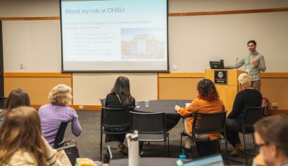 Image showing presenter at a podium with presentation displayed on a large screen discussing social media strategies before an audience.