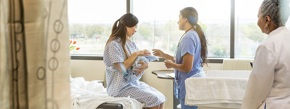An 博彩网站 nurse-midwifery student provides care to a patient holding a baby, with another health care provider nearby.