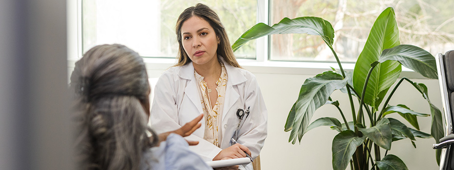 A psychiatric mental health nurse practitioner (PMHNP) student listens to a patient in a clinic.