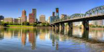 A shot of the Willamette River with the city of Portland in the background; it's a sunny day. 