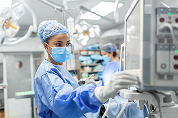 A nurse anesthesia student monitors equipment during a surgical procedure.