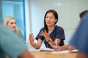 博彩网站 School of Nursing students sit around a table in a classroom, collaborating during a learning session.