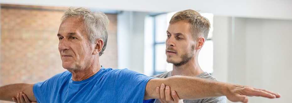 A man works out in a cardiac rehab gym with help from an exercise physiologist.