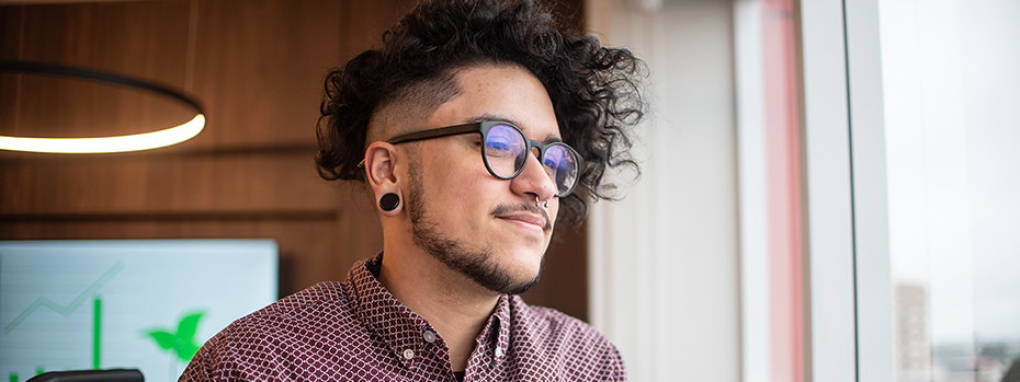 A transgender man looks out the window in a conference room.