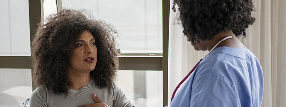 A transgender woman talks with a nurse in an exam room.