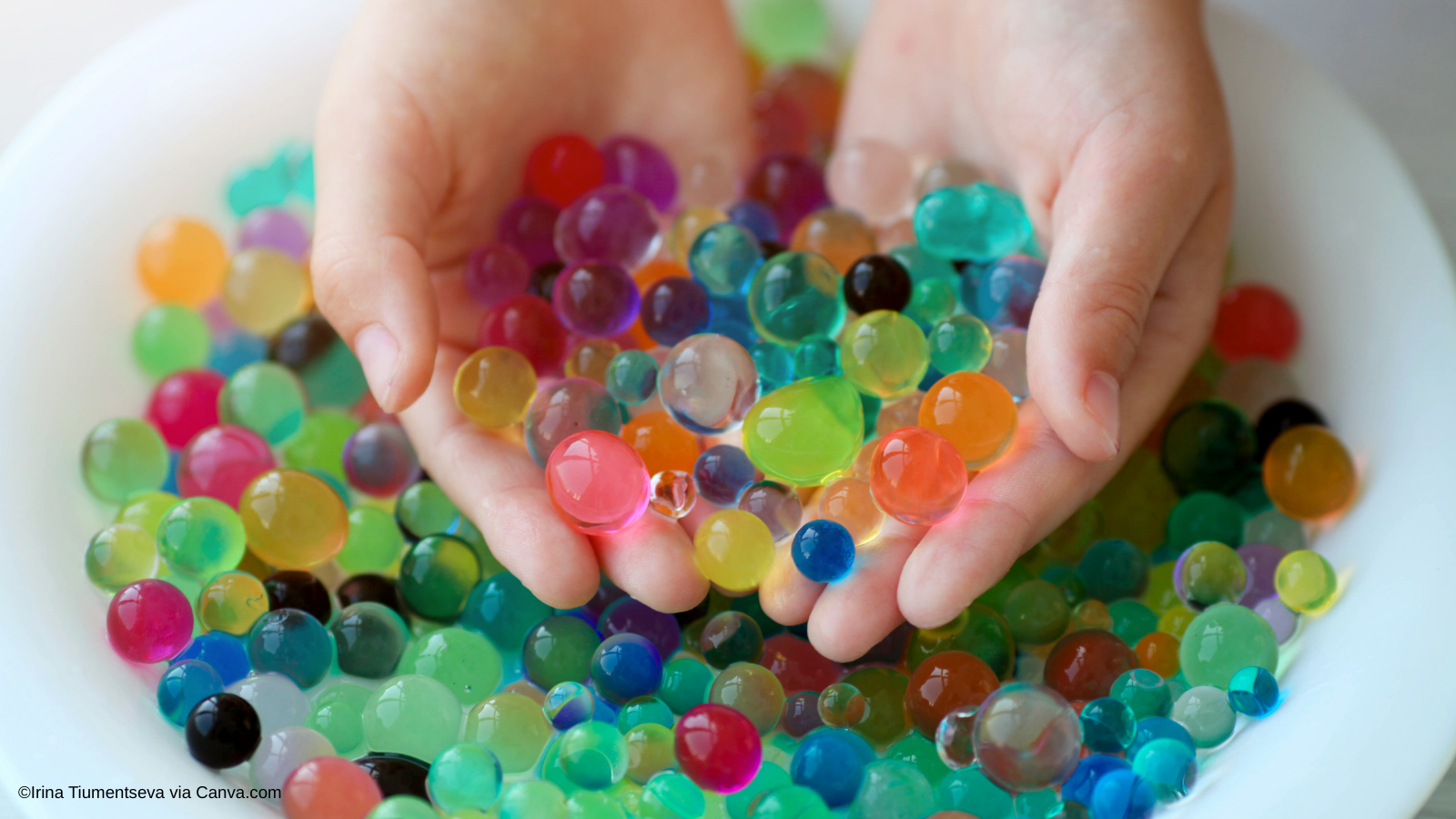 Colorful water beads are held by a child's hands