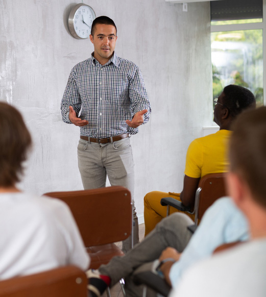 Young man lecturer conducting lesson for group of interested guys sitting in auditorium