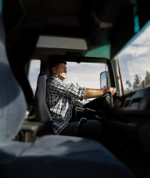 Vertical image, truck driver in the cabin on bright sunny day, looking ahead