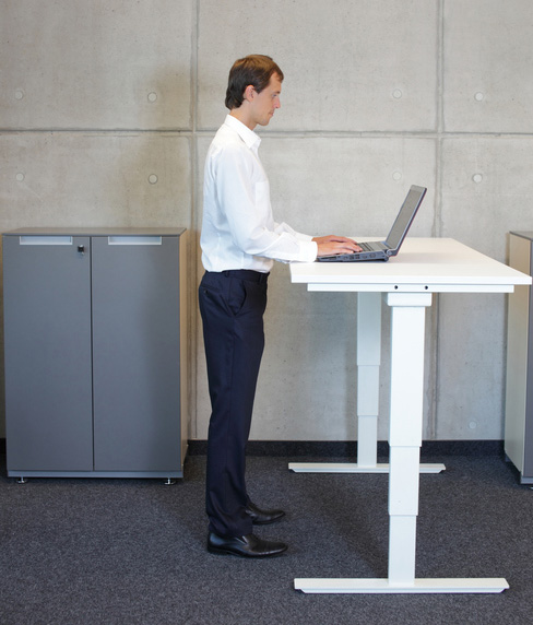 business man in white shirt standing at electrically controlled height adjustment table - full extended - working with laptop