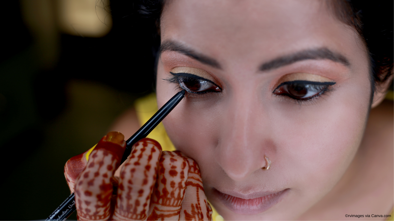 Young woman applies make-up with eye pencil.