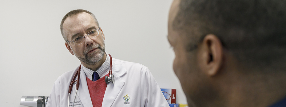 An 博彩网站 doctor listens to a patient in an exam room.