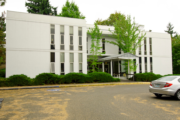 White building with a parking lot in front of it White building with a parking lot in front of it
