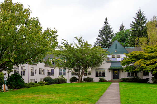 White building with a green awning surrounded with trees White building with a green awning surrounded with trees