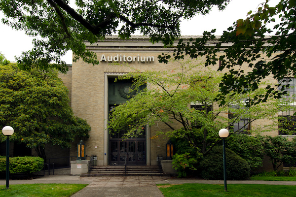 Brick building surrounded with trees with an Auditorium sign on the outside Brick building surrounded with trees with an Auditorium sign on the outside